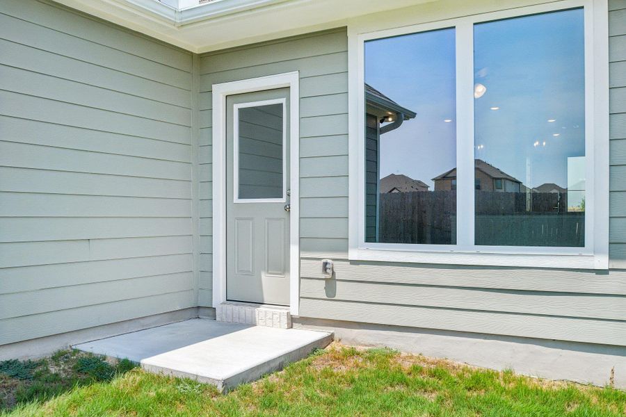 Horizontal lap siding and a concrete stoop line the rear exterior entryway.