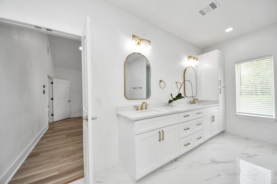 Elegant Primary Bathroom featuring a double vanity with gold accents, marble countertops, and a spacious layout with ample natural light. Elegant Primary Bathroom featuring a double vanity with gold accents, marble countertops, and a spacious layout with ample natural light.