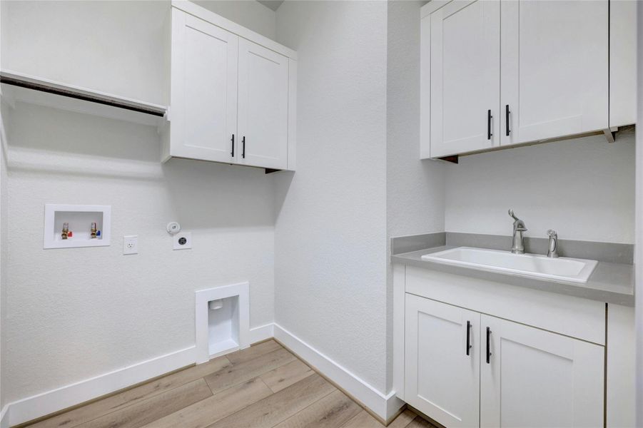 Washroom featuring light wood-style flooring, hookup for a gas dryer, cabinet space, and hookup for a washing machine Washroom featuring light wood-style flooring, hookup for a gas dryer, cabinet space, and hookup for a washing machine