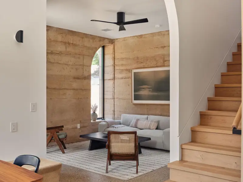 Living area with stairs, a ceiling fan, and speckle aggregate flooring Living area with stairs, a ceiling fan, and speckle aggregate flooring