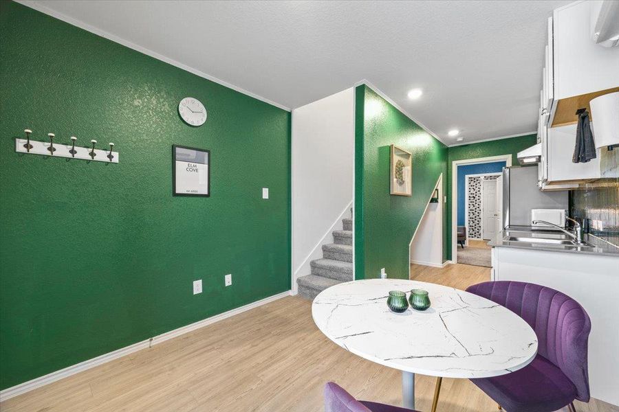 Dining area with light wood-type flooring, crown molding, recessed lighting, and a textured wall Dining area with light wood-type flooring, crown molding, recessed lighting, and a textured wall