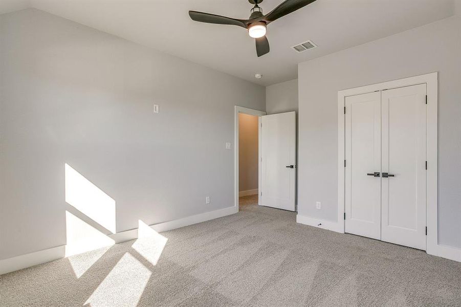 Unfurnished bedroom featuring light colored carpet, ceiling fan, and a closet