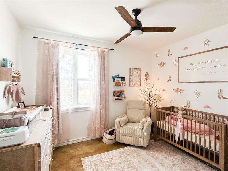 Bedroom featuring a crib, ceiling fan, and light carpet Bedroom featuring a crib, ceiling fan, and light carpet