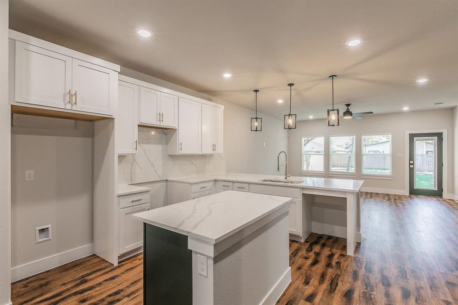 Kitchen featuring decorative backsplash, a kitchen island, sink, dark hardwood / wood-style floors, and white cabinetry