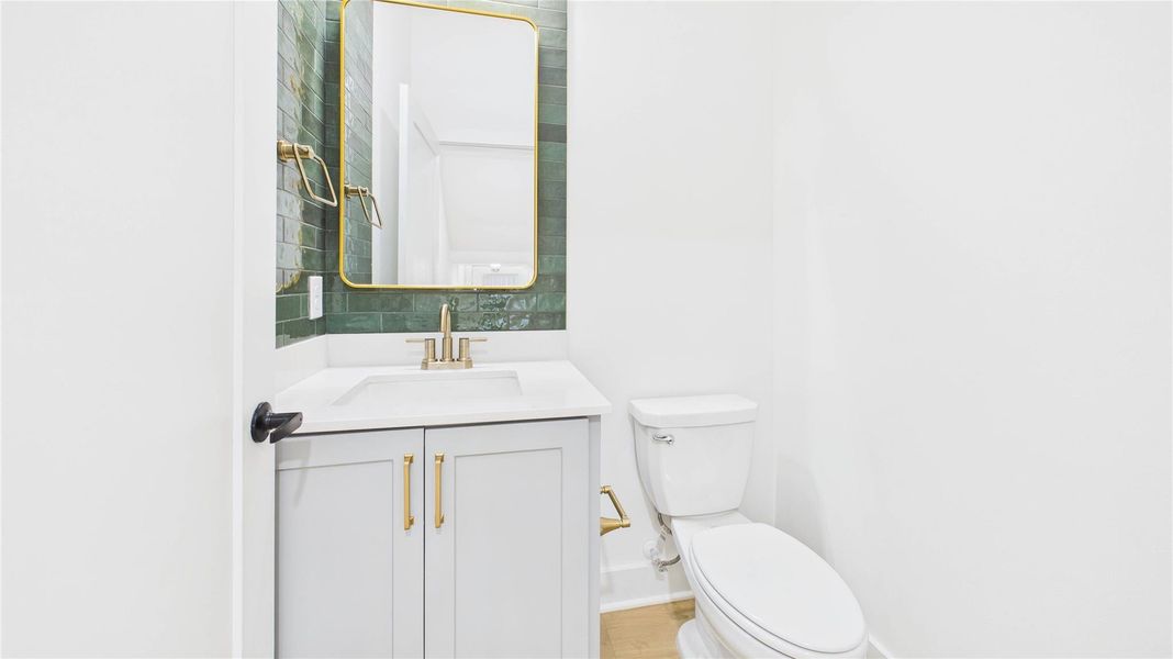 First floor half bath has sleek finishes and storage.