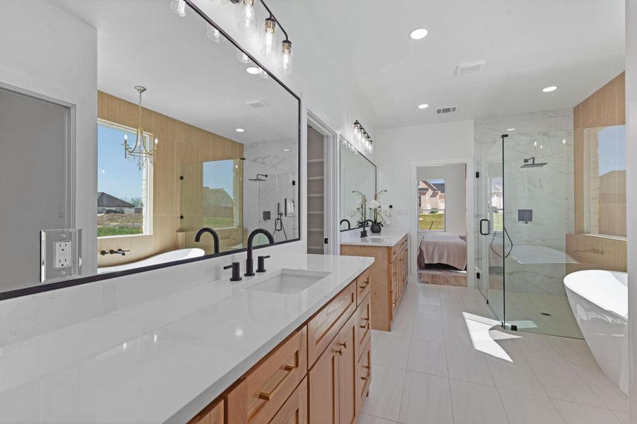 Ensuite bathroom with a freestanding bath, two vanities, a marble finish shower, light tile patterned flooring, and plenty of natural light Ensuite bathroom with a freestanding bath, two vanities, a marble finish shower, light tile patterned flooring, and plenty of natural light