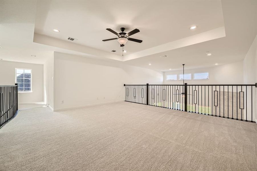 Carpeted spare room with a tray ceiling and ceiling fan