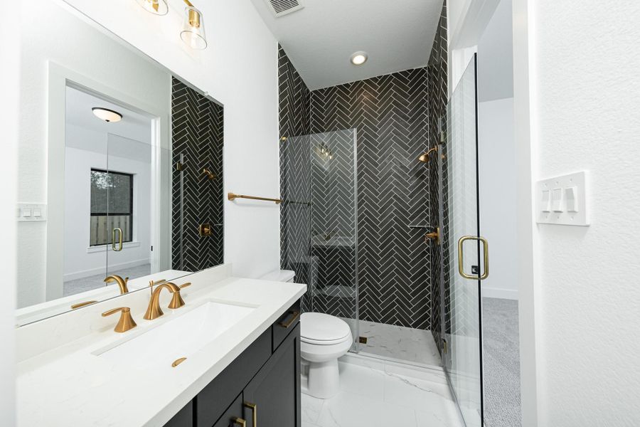 The ensuite secondary bathroom features a modern vanity, large framed walk-in shower with tile surround, and modern brushed gold finishes.