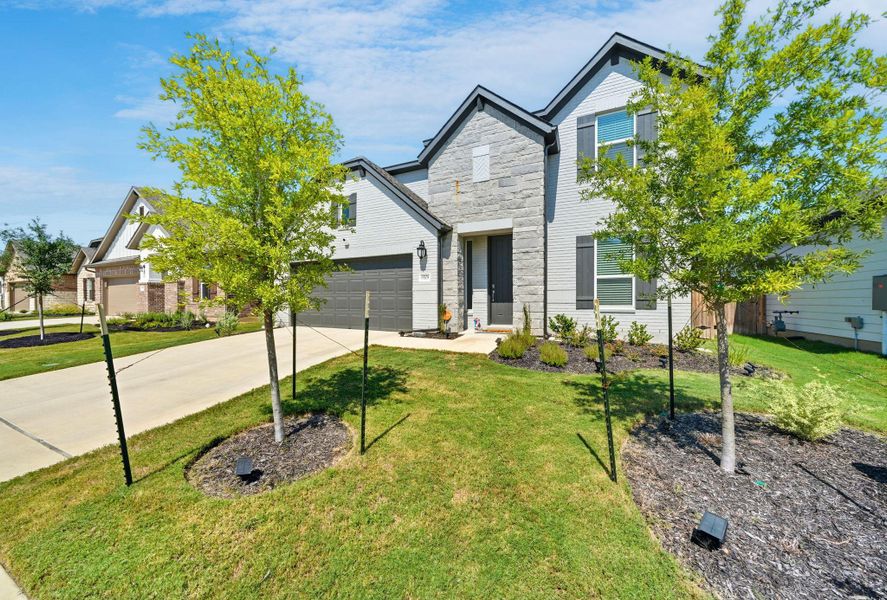 Traditional-style home featuring a front lawn, concrete driveway, and stone siding Traditional-style home featuring a front lawn, concrete driveway, and stone siding