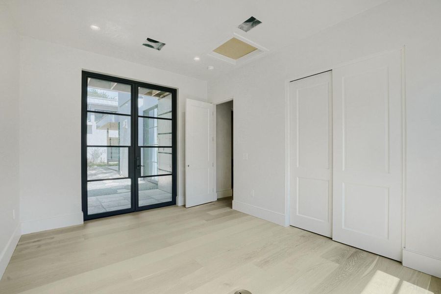 Light wood flooring and bright white walls create an airy bedroom with patio access.