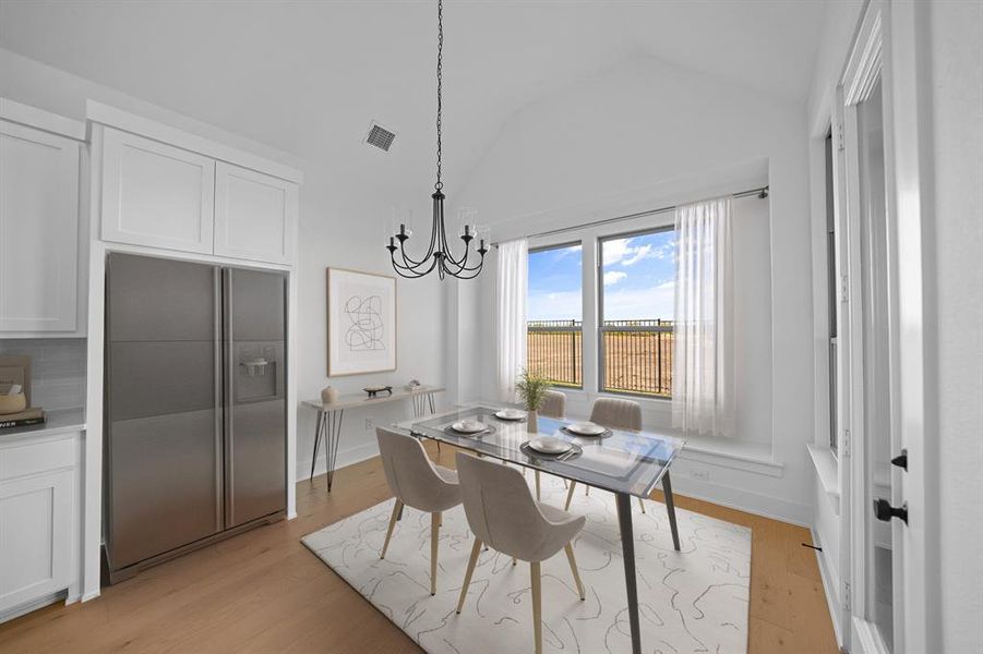 Dining area with lofted ceiling, light wood-type flooring, and a chandelier