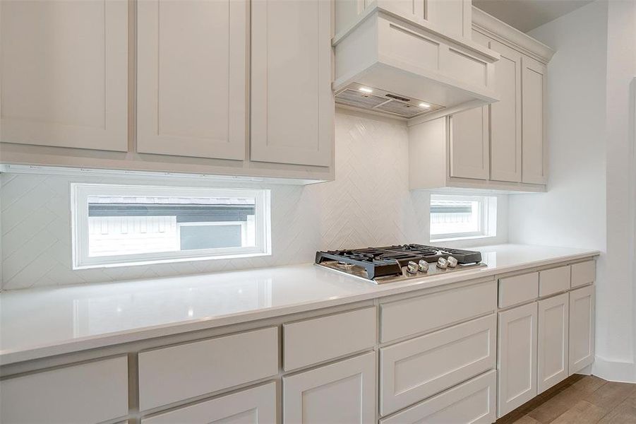 Kitchen featuring white cabinetry, stainless steel gas cooktop, custom exhaust hood, and wood-type flooring