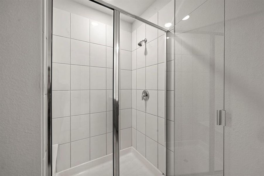 Bathroom featuring a shower stall and a textured wall