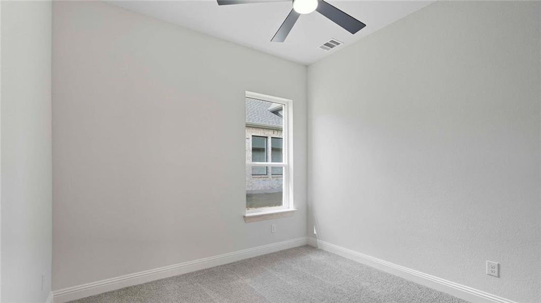 Neutral-toned interior featuring a single window, a ceiling fan, and light gray carpeting