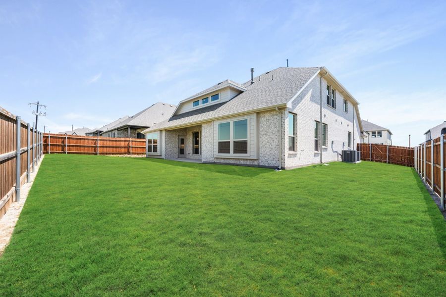 Two-story brick home with large grassy backyard enclosed by wood privacy fence Two-story brick home with large grassy backyard enclosed by wood privacy fence
