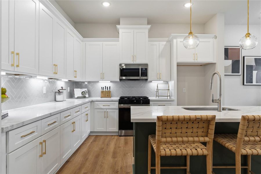 A composition of texture and tone, where a bold accent island grounds the space. Brass detailing, herringbone tilework, and integrated lighting add dimension, while soft close cabinetry reinforces a seamless finish. A composition of texture and tone, where a bold accent island grounds the space. Brass detailing, herringbone tilework, and integrated lighting add dimension, while soft close cabinetry reinforces a seamless finish.