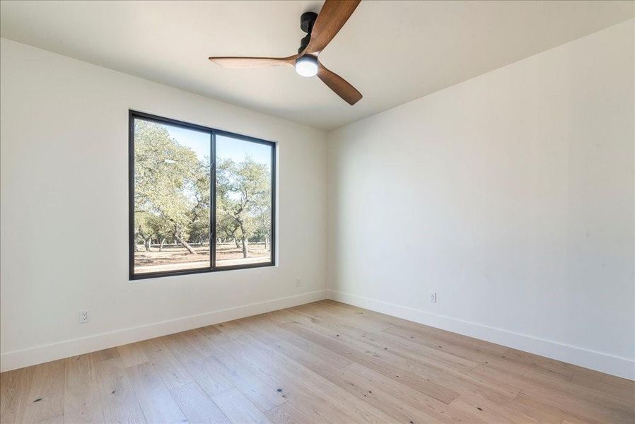 One of the guest bedrooms is exceptionally spacious, featuring high ceilings, upgraded ceiling fans, and a walk-in closet.