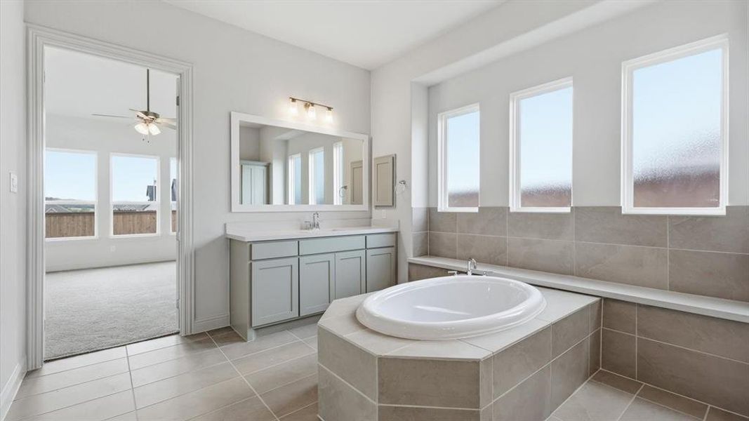 Soaking tub with tiled surround, flanked by three rectangular windows