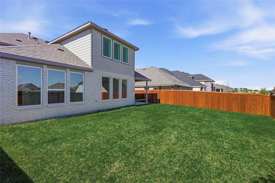 Back of property with brick siding, a fenced backyard, and a shingled roof