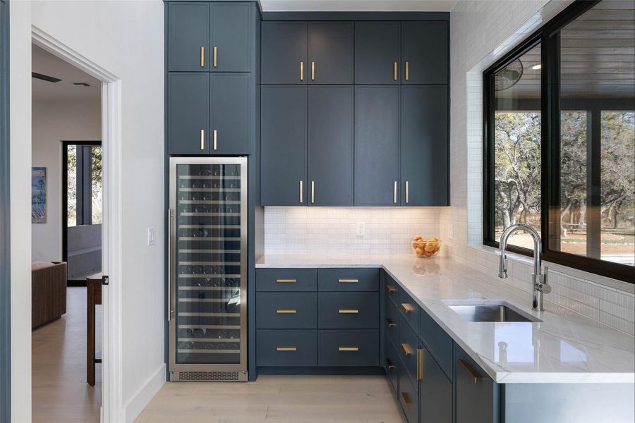 Kitchen featuring light stone countertops, wine cooler, light wood-type flooring, and tasteful backsplash