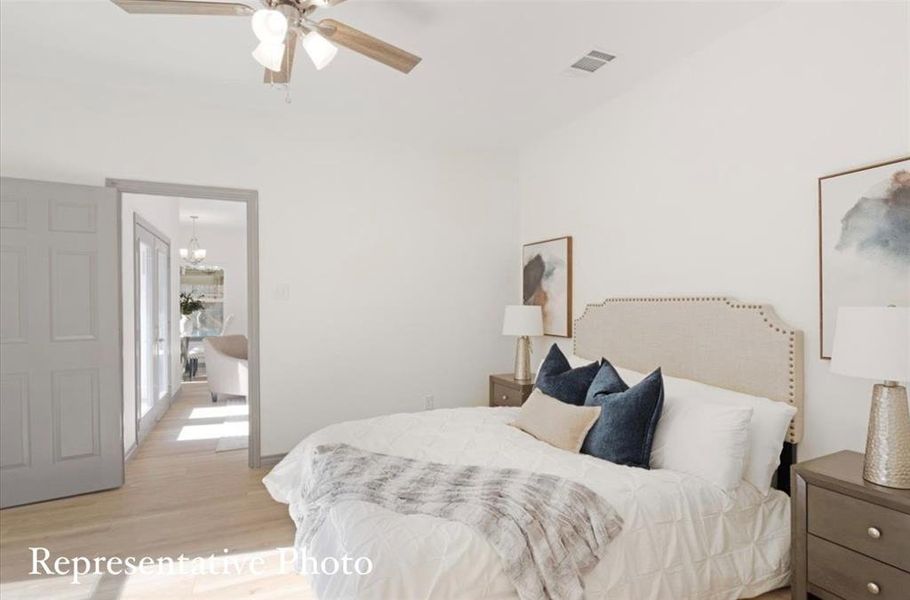 Bedroom featuring light hardwood / wood-style floors and ceiling fan with notable chandelier