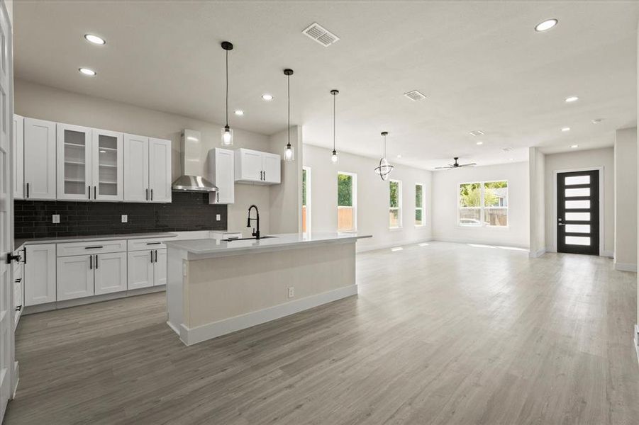 Kitchen with glass insert cabinets, decorative backsplash, white cabinetry, decorative light fixtures, and open floor plan Kitchen with glass insert cabinets, decorative backsplash, white cabinetry, decorative light fixtures, and open floor plan