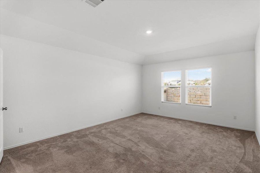 Carpeted spare room featuring baseboards and lofted ceiling