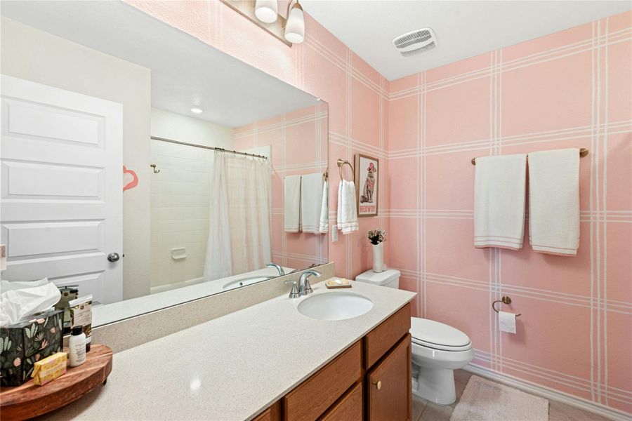 This full bathroom offers a bright and inviting design, featuring a tub/shower combination, an extra-long vanity for ample counter space, and beautifully curated decorative walls and lighting that enhance its stylish appeal.