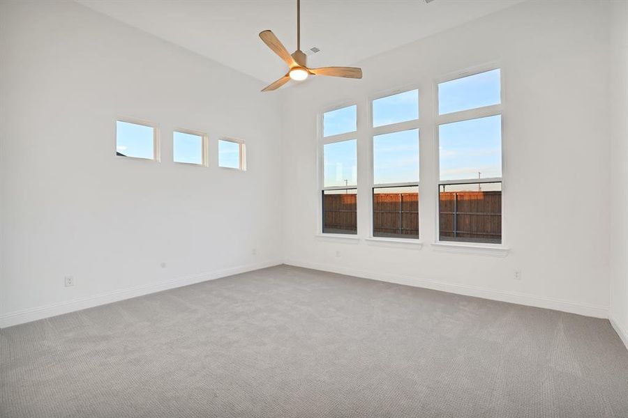 Primary bedroom featuring a towering ceiling, carpet floors, and ceiling fan