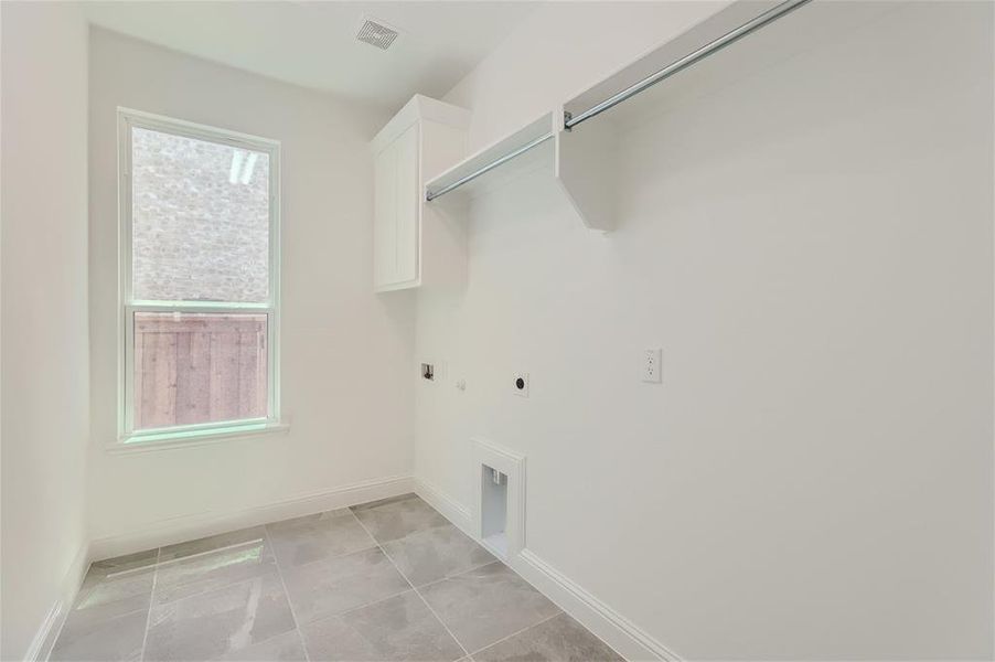 Laundry area with hookup for a gas dryer, cabinets, light tile flooring, and hookup for an electric dryer