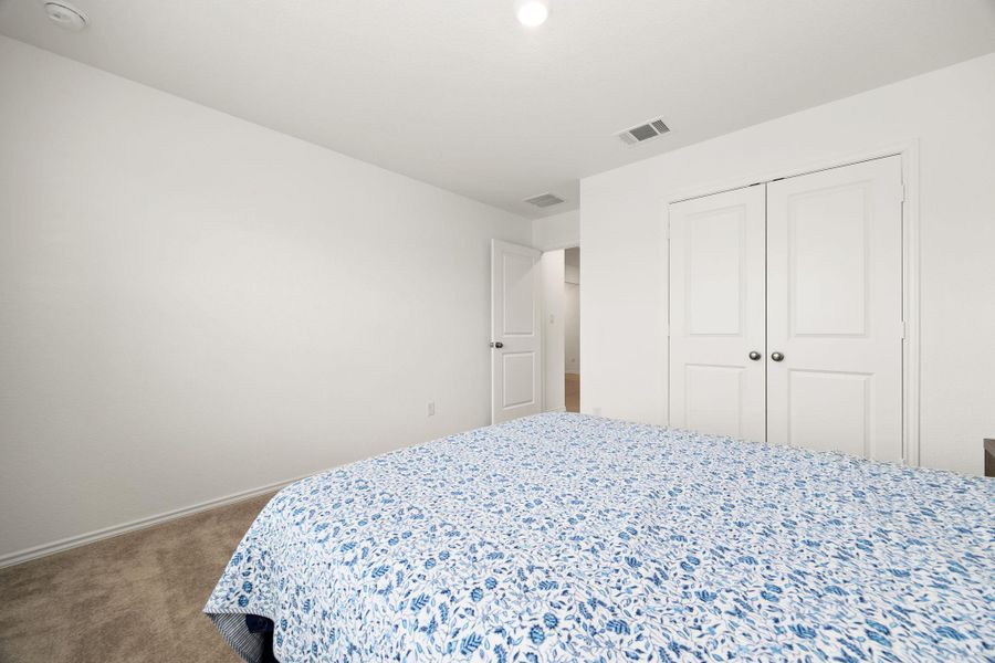 A well-lit bedroom features plush carpeting and white bi-fold closet doors, enhancing its ready-to-move-in appeal.