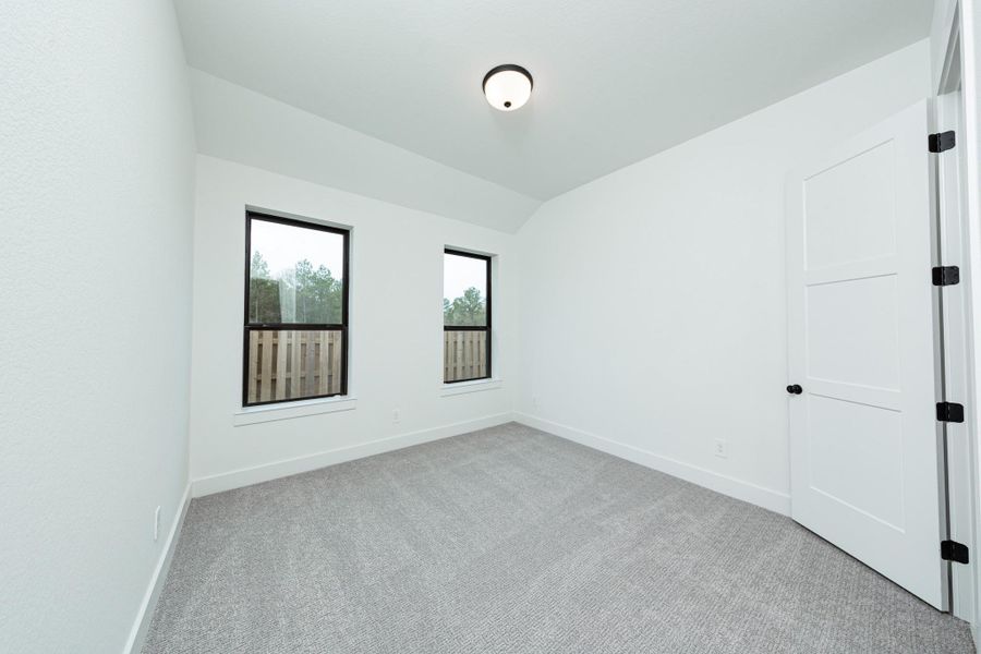 The Guest Suite features a sloped ceiling, plush carpet flooring, large windows, an ensuite secondary bathroom with a walk in closet.