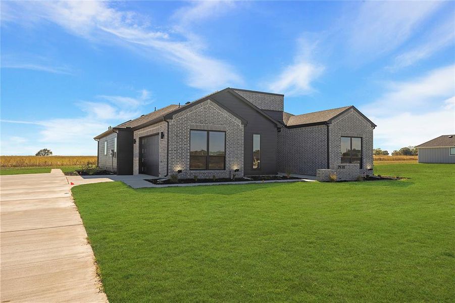 Back of property with brick siding, a yard, driveway, and a garage Back of property with brick siding, a yard, driveway, and a garage