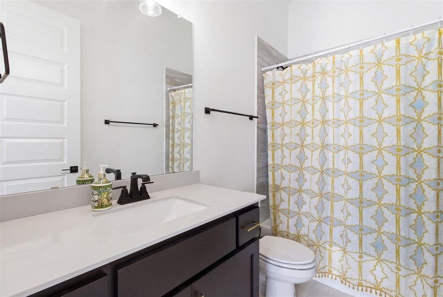 Bathroom featuring a dark wood vanity with a light-toned countertop, an integrated rectangular sink, and matte black fixtures