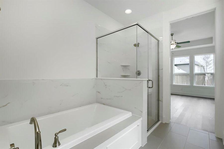 Contemporary bath featuring a built-in tub with brushed nickel fixtures, a frameless glass shower enclosure, and white marble-look tile surround