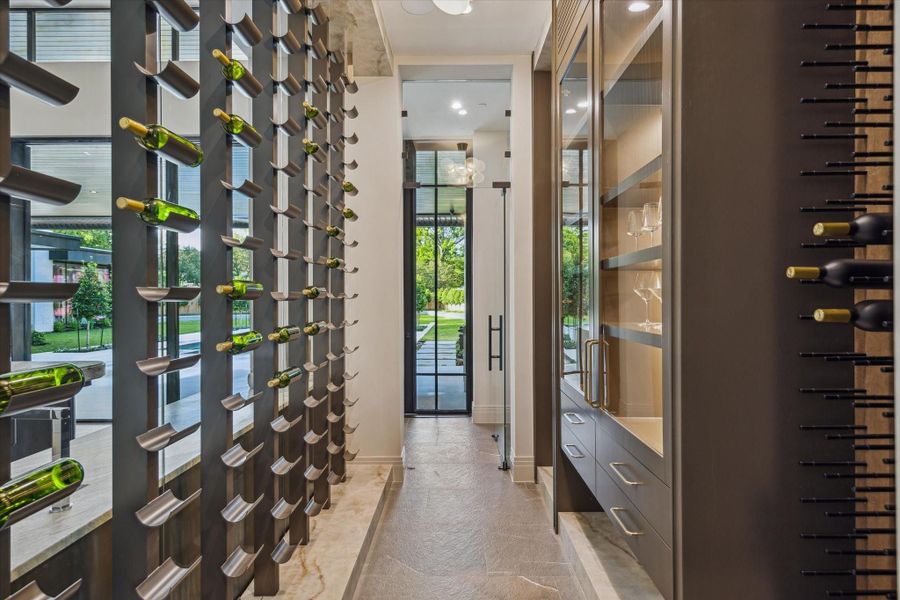 This climate-controlled wine room is Oenophile's dream, offering storage for approximately 615 bottles within a custom wood racking system. Appointed with Lumix matte porcelain countertops, Piasentina flamed natural tile, and enclosed by a striking glass and steel entry door, this space blends high-end design with functional luxury.