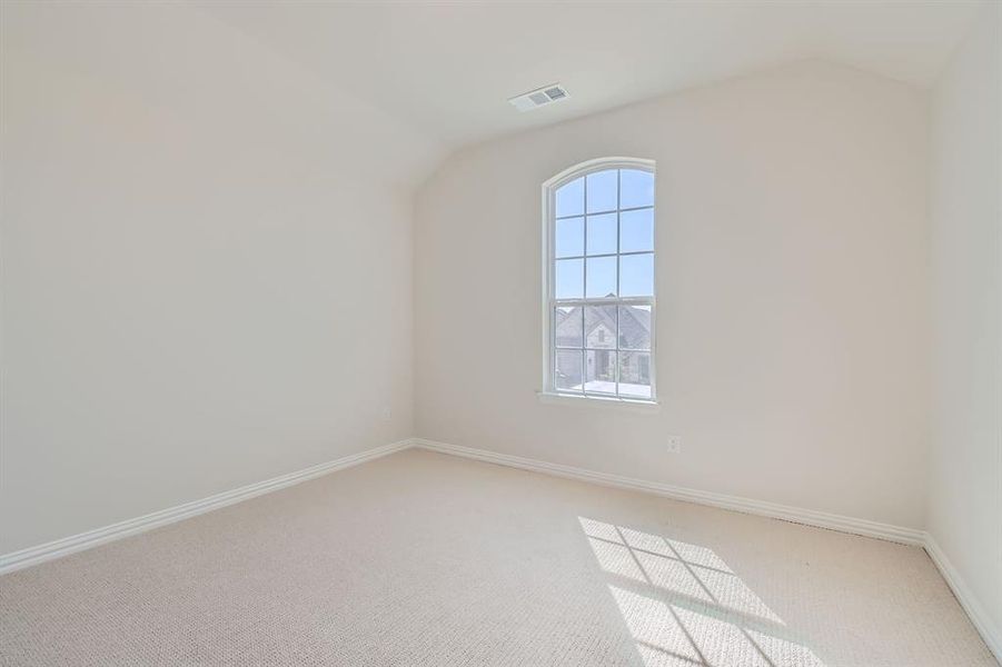 Empty room with lofted ceiling and carpet flooring