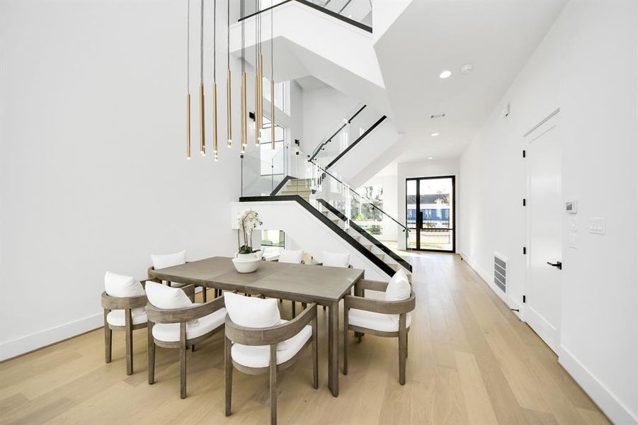 Bright and inviting dining area with soaring ceilings and modern design elements. The open layout, enhanced by glass railings and natural light, provides a perfect space for gatherings and stylish dining experiences.