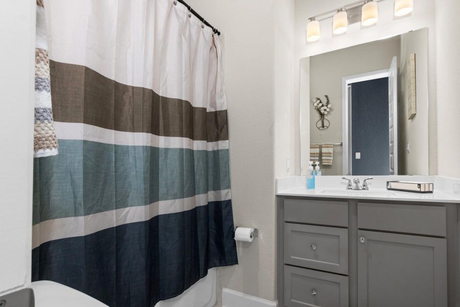 Bright, modern bathroom featuring a vanity with a large mirror and stylish lighting.