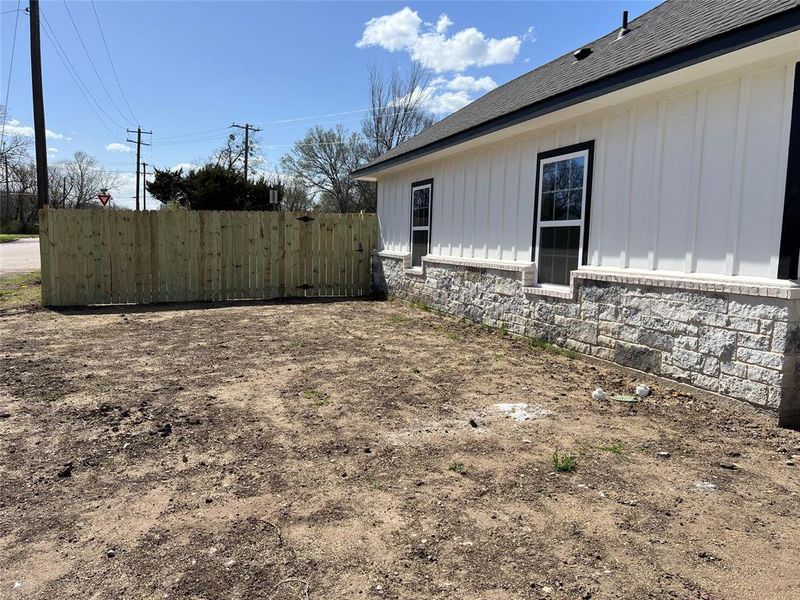 View of home's exterior with stone siding, board and batten siding, a shingled roof, and fence