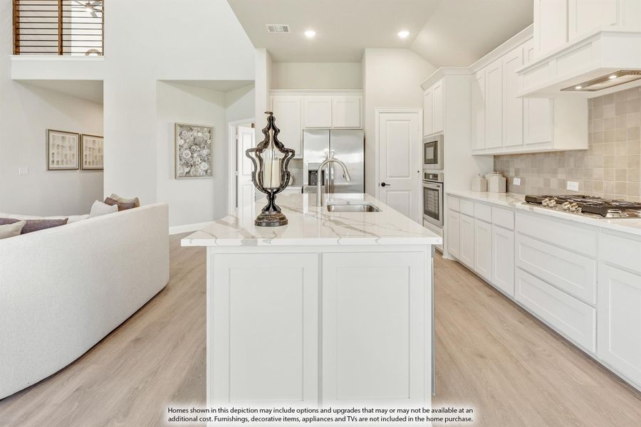 Open kitchen with white cabinets, marble island, stainless appliances, and light wood floors open to living area Open kitchen with white cabinets, marble island, stainless appliances, and light wood floors open to living area