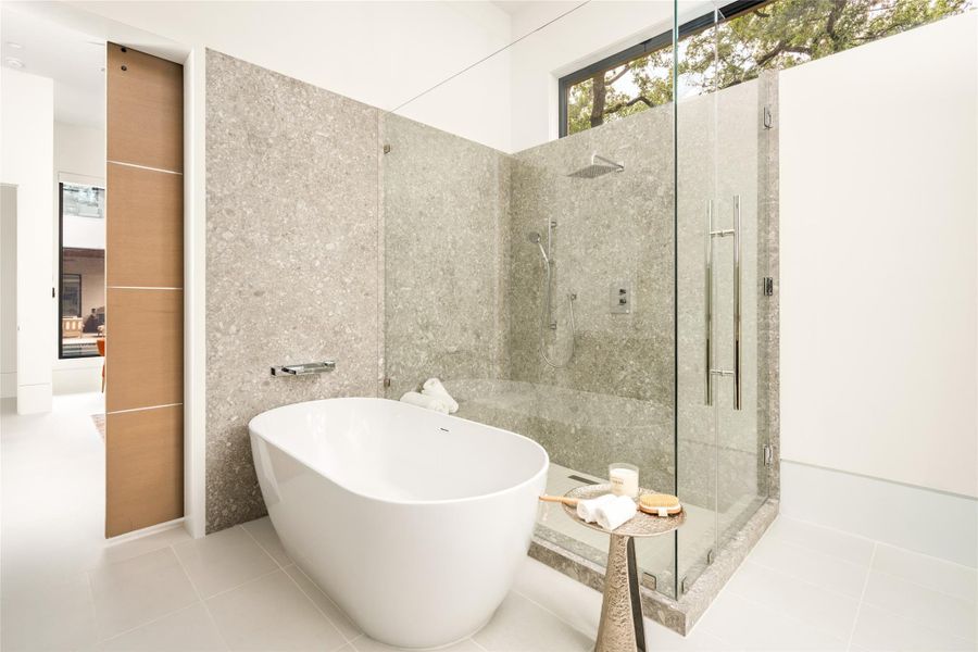 Beautifully appointed bath featuring a freestanding soaking tub, glass-enclosed shower, and natural stone finishes.