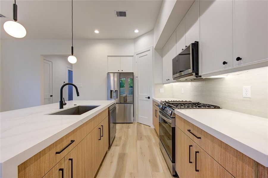 This stunning kitchen features upgraded quartz countertops (2" thick laminated edges), large pantry, waterfall island, sleek modern cabinetry, and stainless steel smart appliances, including the craft ice refrigerator!