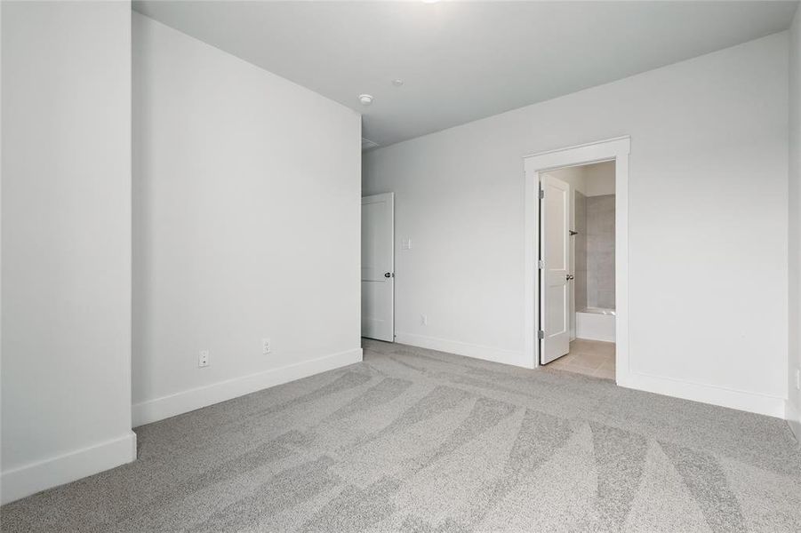 Unfurnished bedroom with light carpet and ensuite bath