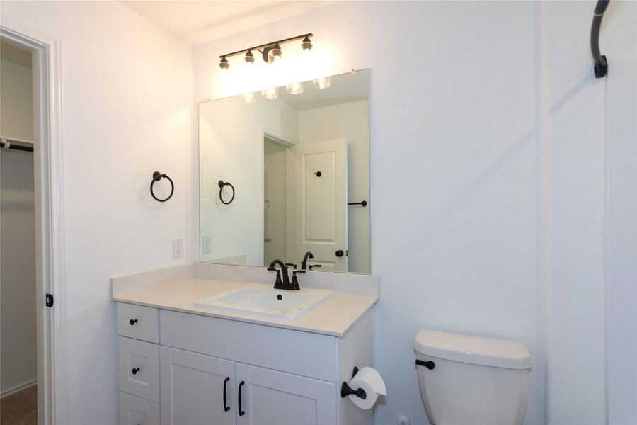 Primary bathroom featuring a vanity with white cabinetry, a light-toned countertop, and black hardware