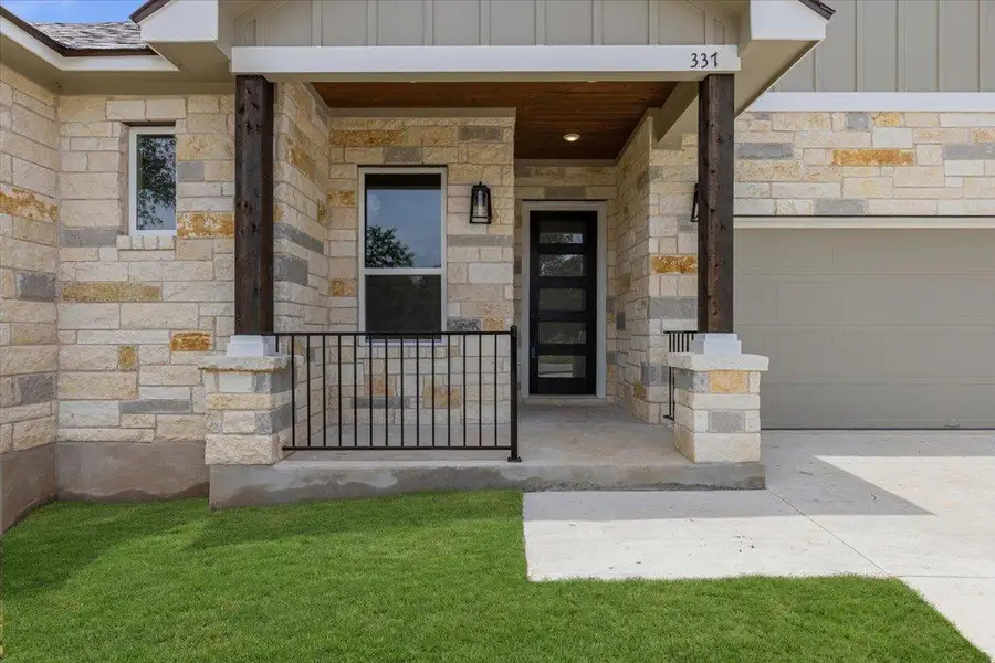 A welcoming front entrance features natural stone, a dark wood support beam, and a modern paneled door. A welcoming front entrance features natural stone, a dark wood support beam, and a modern paneled door.