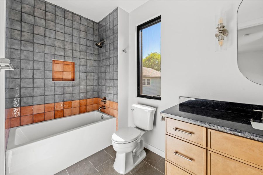 Full bath with  shower combination, vanity, and dark tile patterned flooring