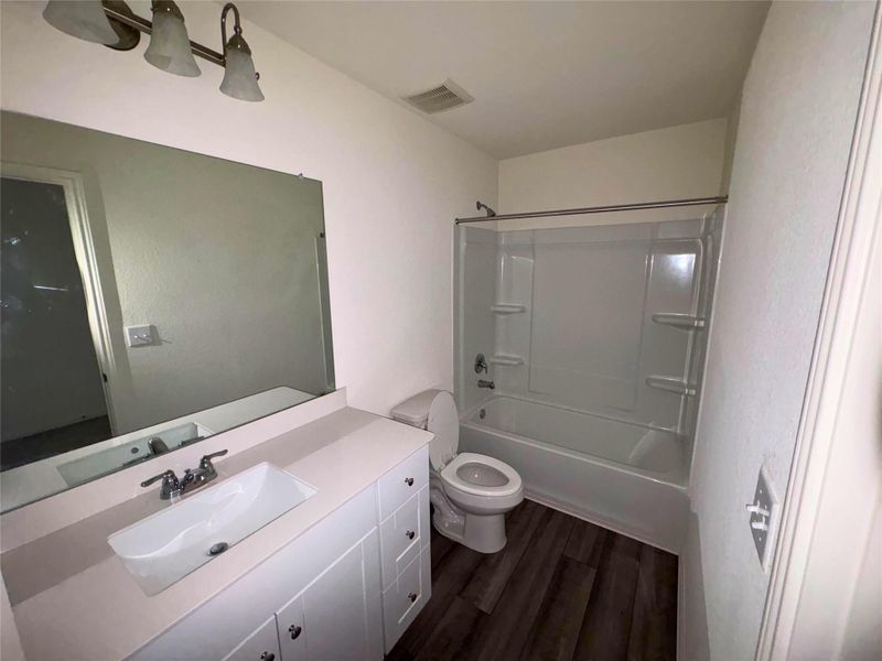 Bathroom featuring vanity, shower combination, and dark wood-style flooring Bathroom featuring vanity, shower combination, and dark wood-style flooring