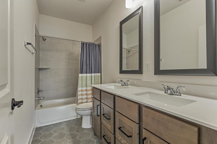 This inviting secondary bathroom boasts a sleek, modern design with dual sinks, chic mirrors, and a practical shower-tub combo, perfect for comfort and convenience.
