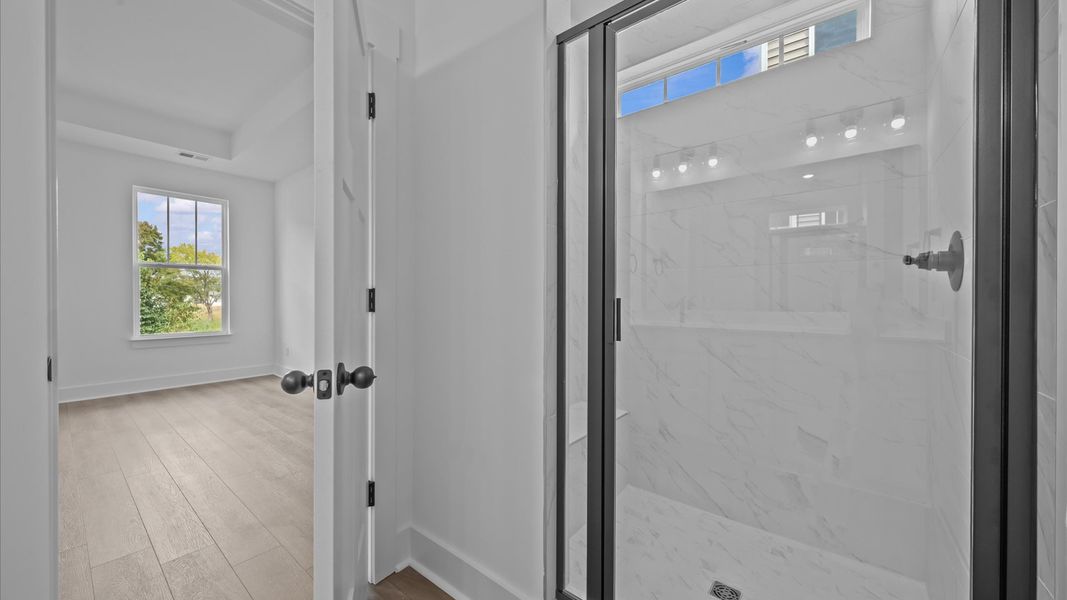 Elegant primary bathroom featuring a spacious tiled walk-in shower and dual vanity in this first-class DRB Homes design Elegant primary bathroom featuring a spacious tiled walk-in shower and dual vanity in this first-class DRB Homes design